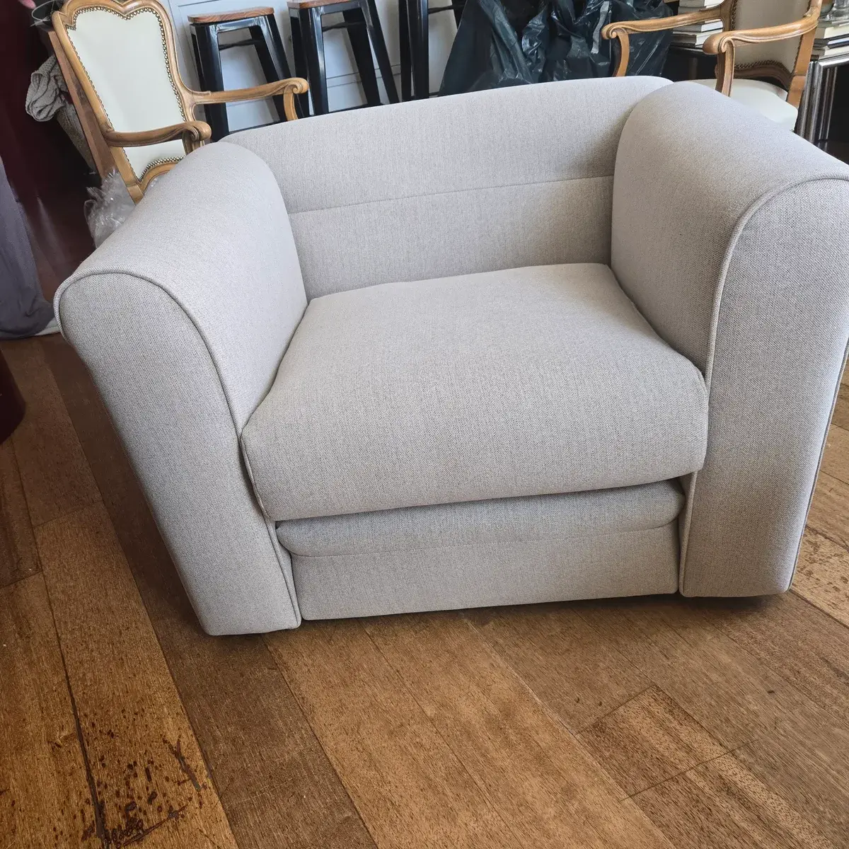 Butaca tapizada en estilo nórdico beige sobre suelo de madera