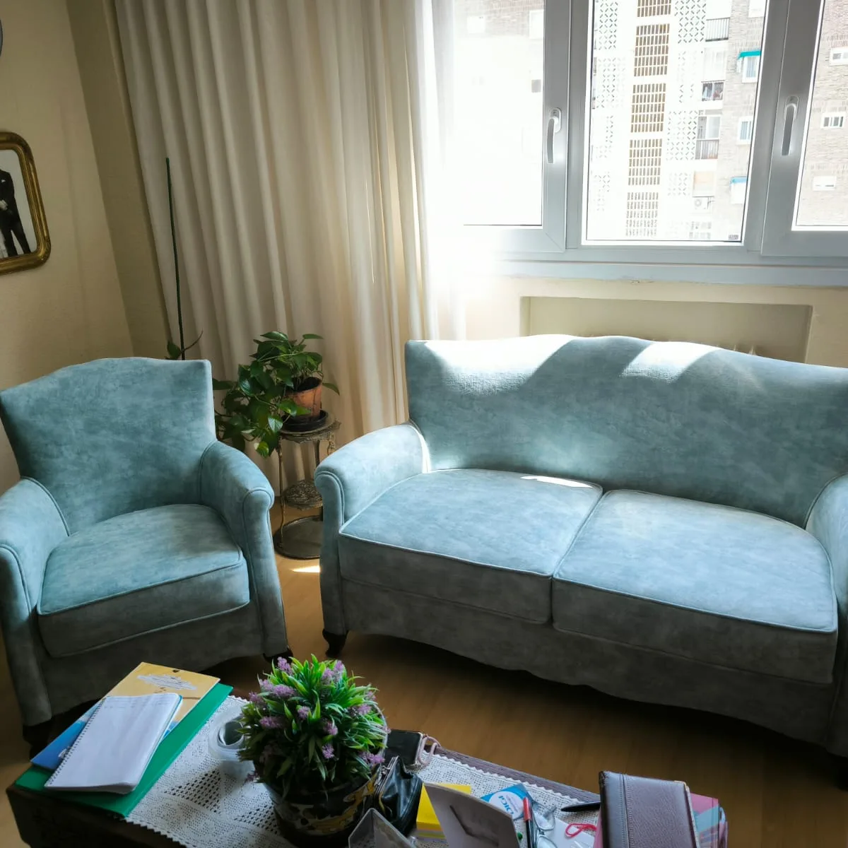 Conjunto sofá y sillón tapizados en terciopelo aqua en salón con ventanal