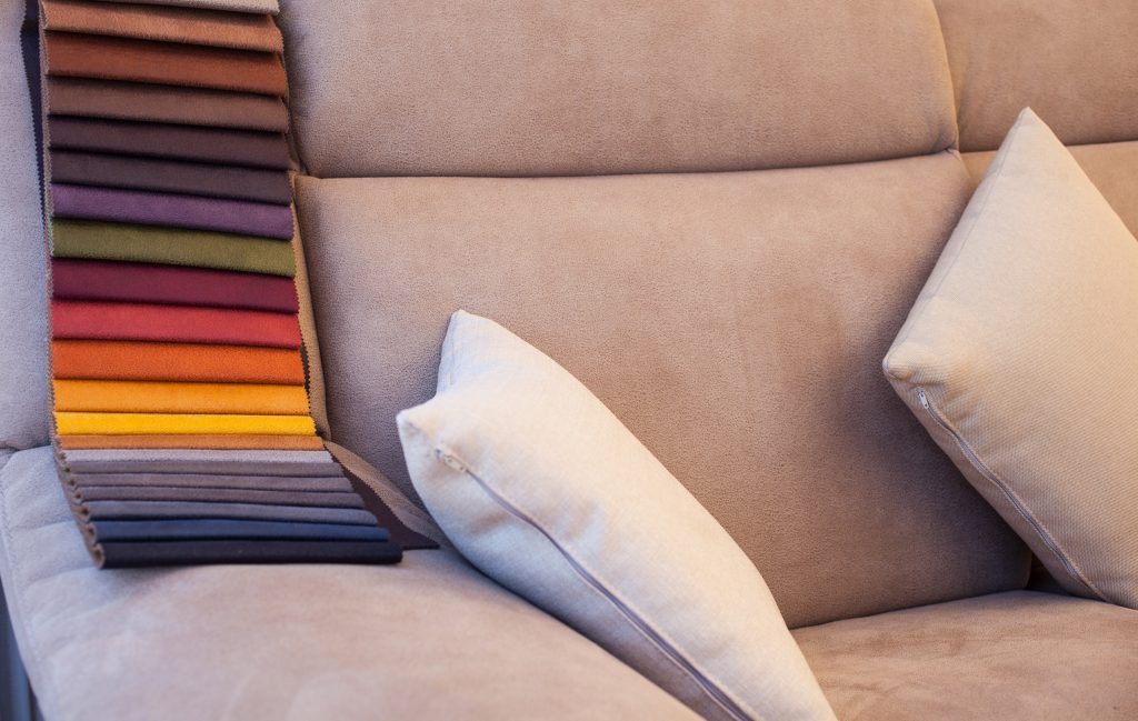 Vemos sobre un sofa un muestrario con diferentes colores y telas