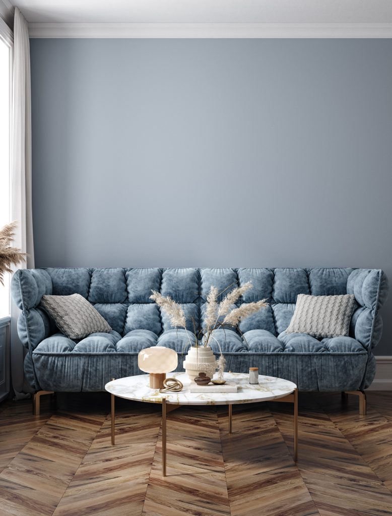 Render final en 3D de un sofá tapizado para cliente final. El sofá es moderno de color azul y con cojines de decoración.